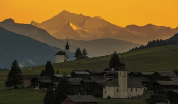 Schweizer Dorf vor Alpenkulisse